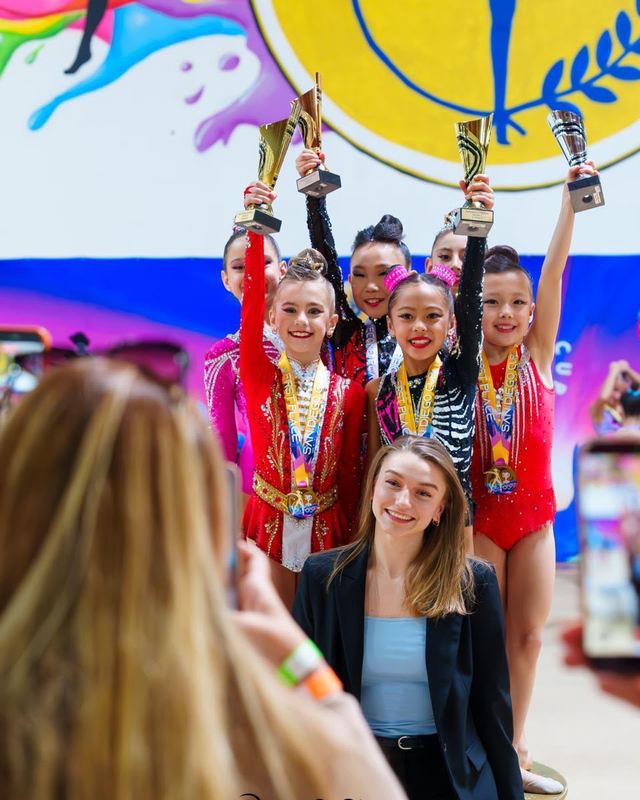 Gymnasts lifting their trophies on the podium